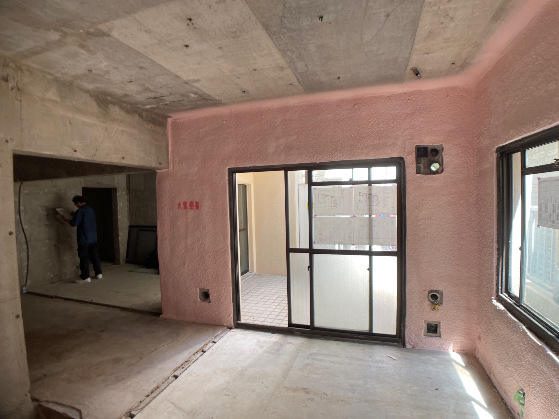 断熱施工中のマンションの壁。外に面した壁のみにピンク色で吹付式の断熱材が施工されている。